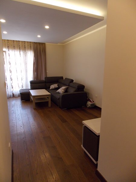 Living room with a corner sofa and parquet flooring in an apartment in Budva, Montenegro. Modern interior with lighting.