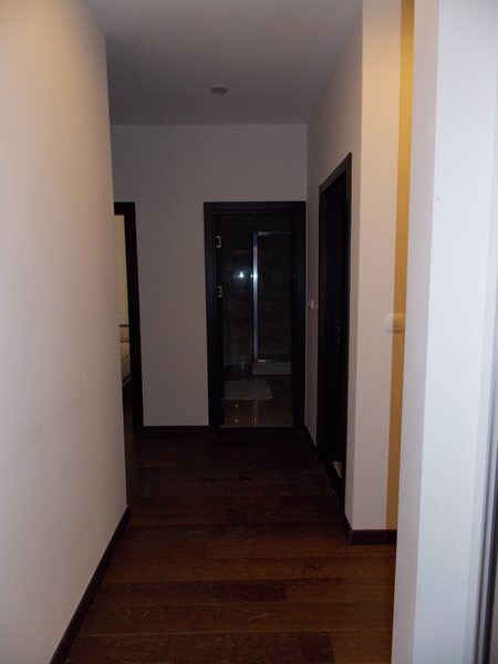 Hallway in a modern apartment in Budva, Montenegro: light walls, dark interior doors, and parquet flooring.