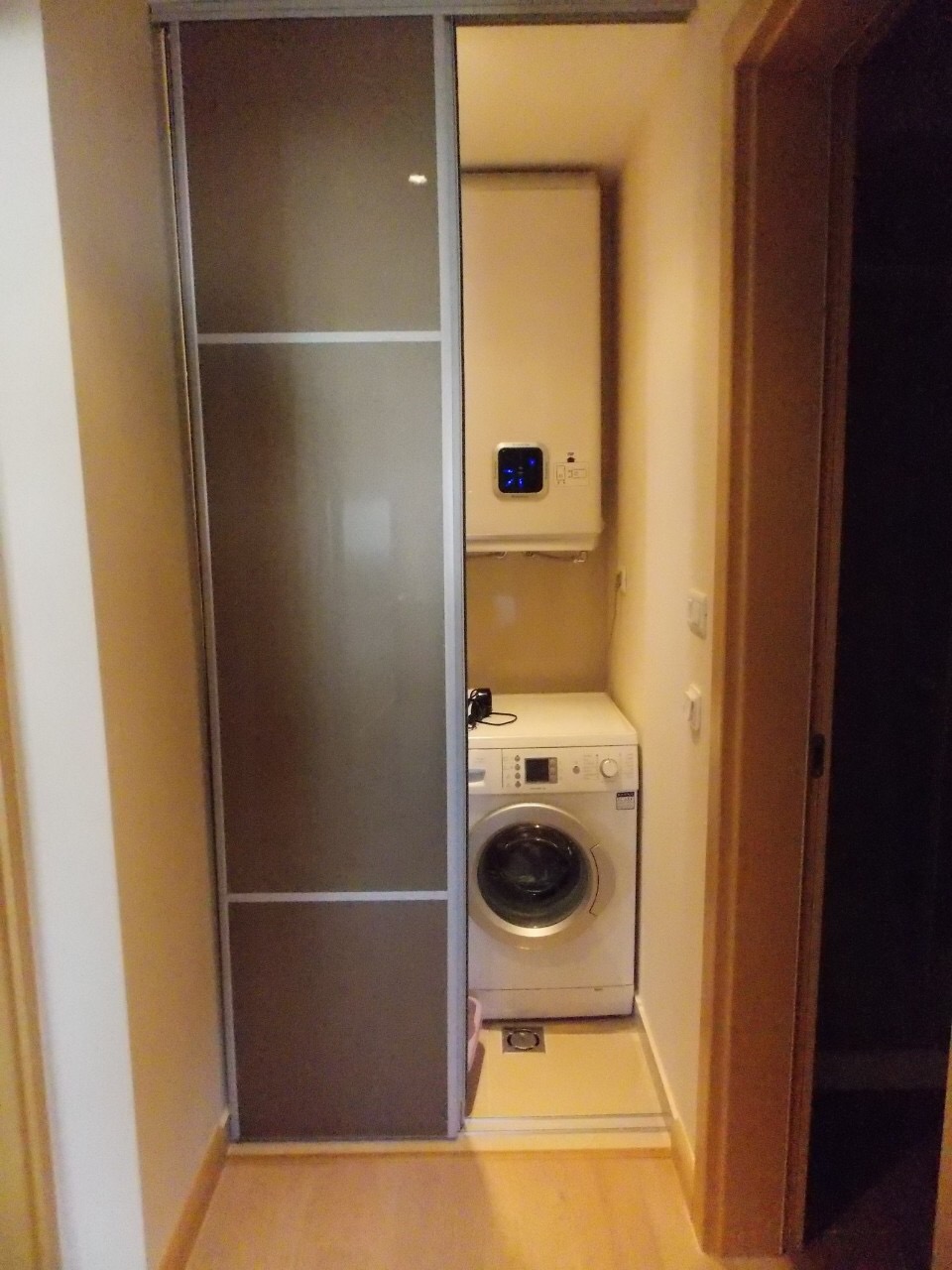 Utility niche with a washing machine and boiler in an apartment in Budva, Montenegro, closed by a sliding door.