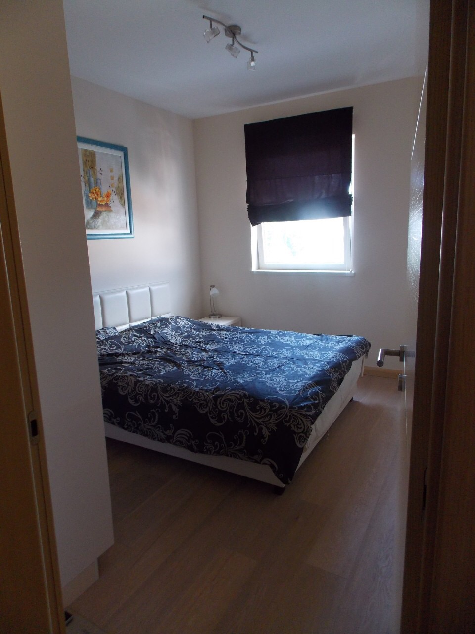Cozy bedroom with a double bed and a bright interior in an apartment for sale in Budva, Montenegro.