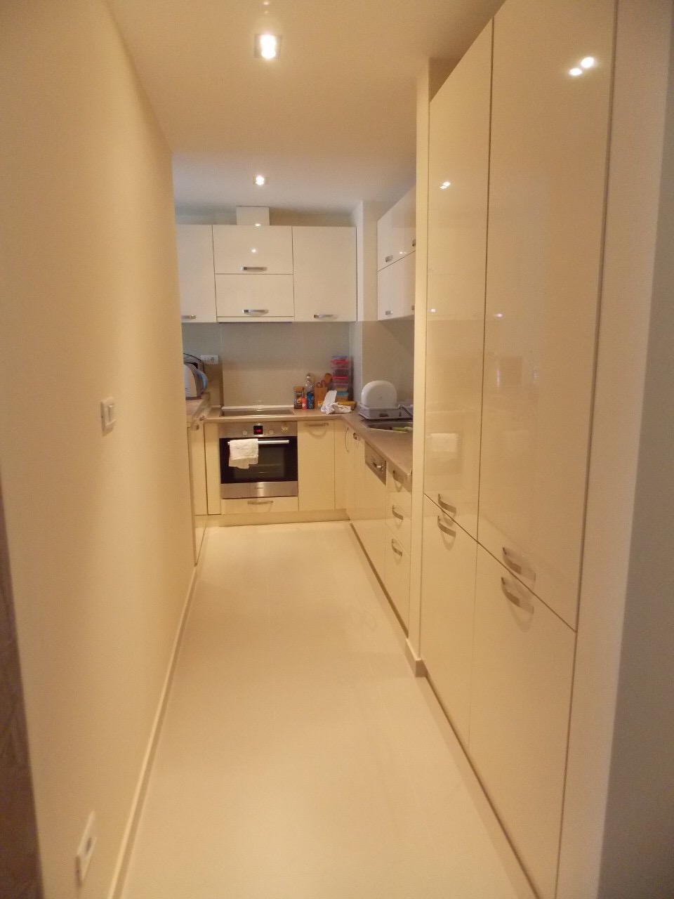 Modern bright kitchen with glossy fronts in an apartment in Budva, Montenegro, with built-in appliances.