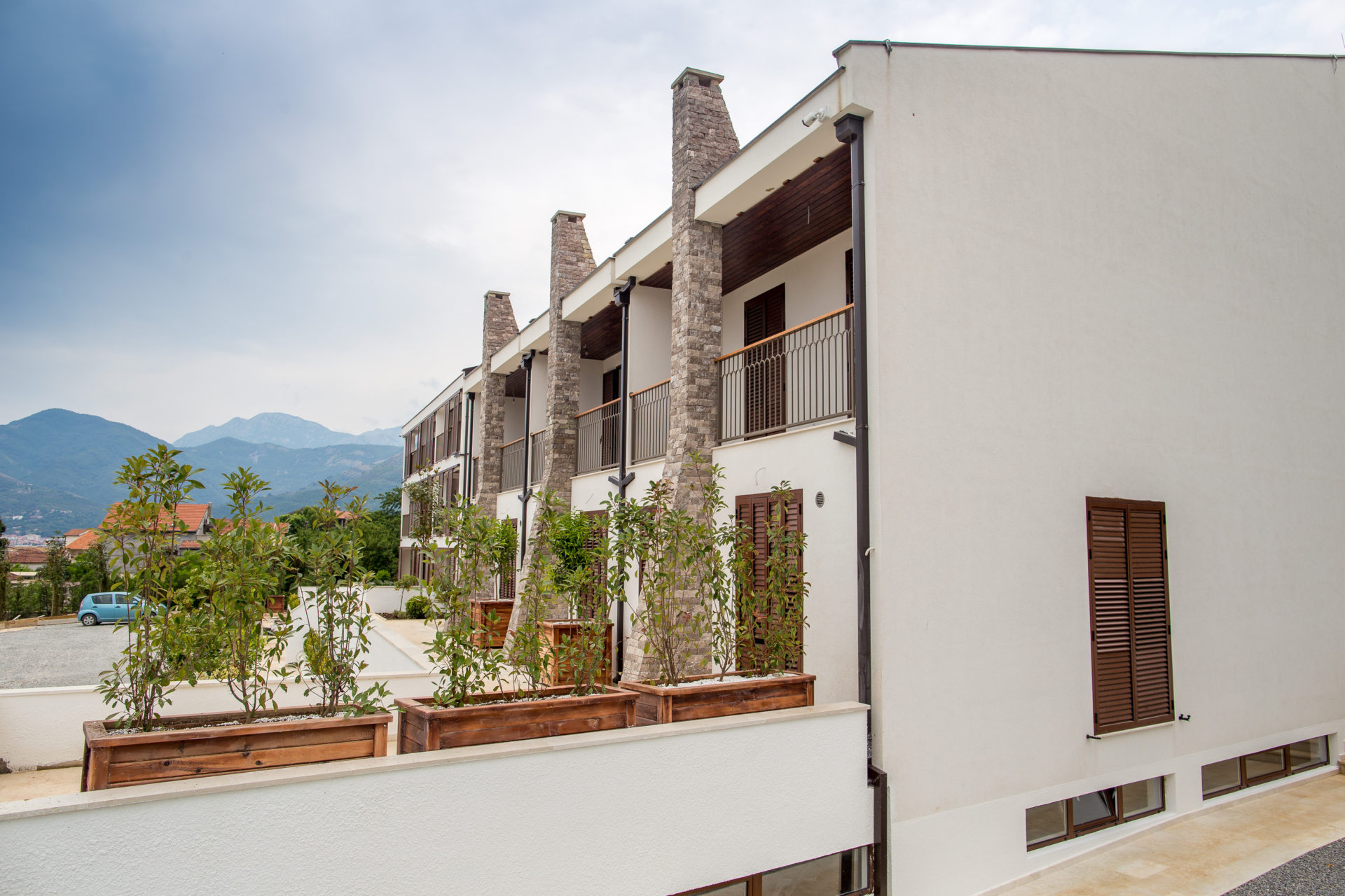 Modern residential complex in Tivat, Montenegro: stone-clad facade, balconies, and mountain views.