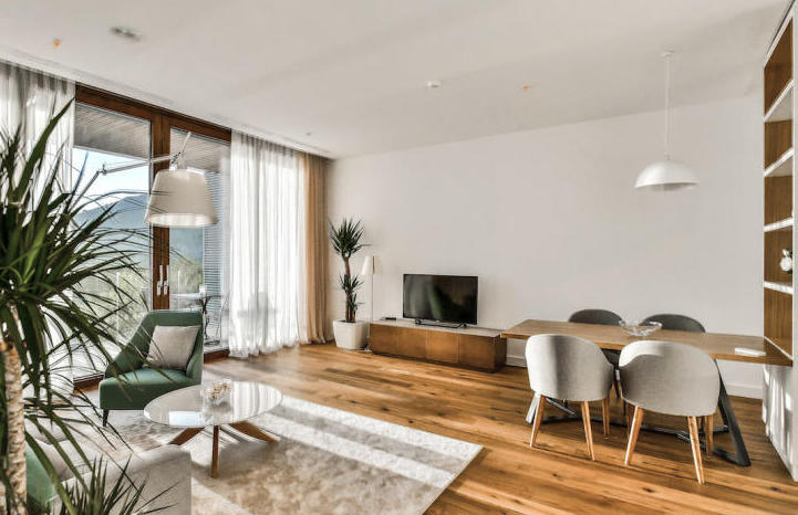 Modern living room with panoramic windows in an apartment in Kamenovo, Montenegro: bright interior, wooden floor, and furniture.