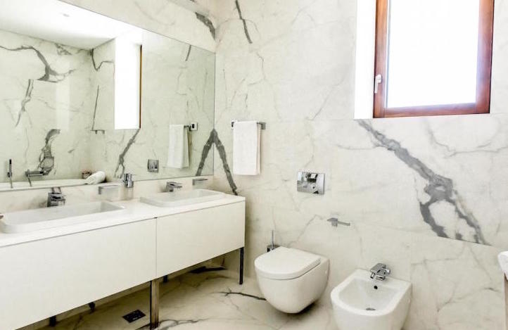 Modern bathroom with white marble finish in an apartment, Kamenovo, Montenegro: two sinks and plumbing fixtures.