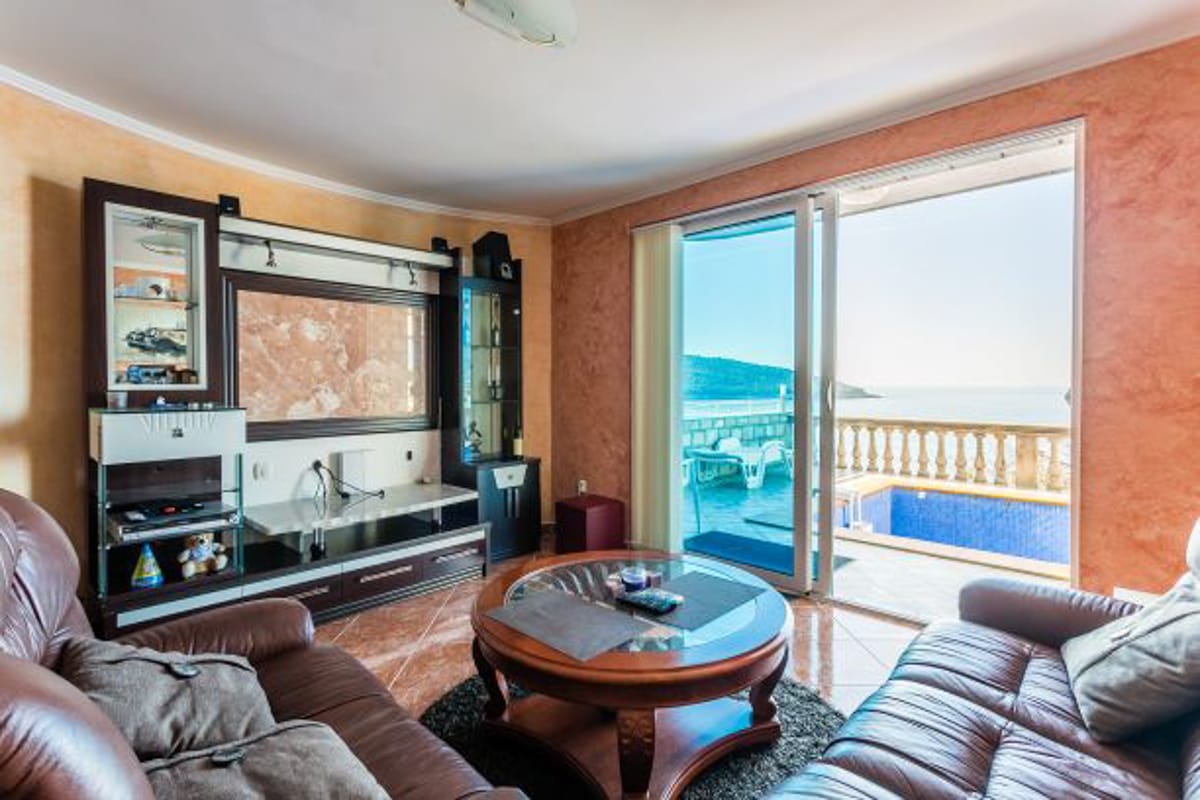 Living room with leather furniture and access to a terrace with a pool and sea view in a house, Kruče, Montenegro.