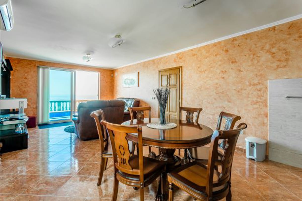 Living room with dining area and sea view in a house, Kruče, Montenegro: wooden furniture, tiled floor, terrace.