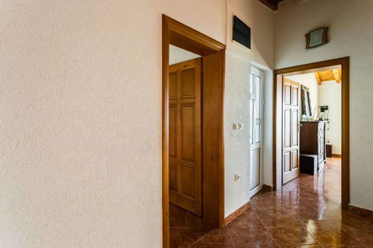 Interior of a house in Kruče, Montenegro: a bright hallway with wooden doors and tiled flooring, view of the living room.