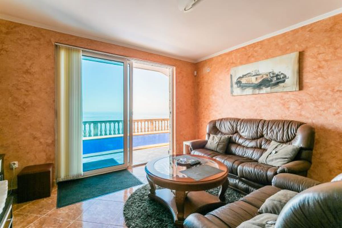 Living room in a house in Kruče, Montenegro: leather sofa, coffee table, and panoramic sea view from the terrace.