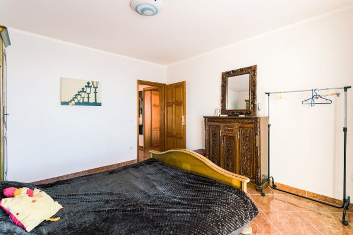 Bedroom in a house in Kruče, Montenegro: a double bed, an ornate dresser with a mirror, and a floor clothes rack.