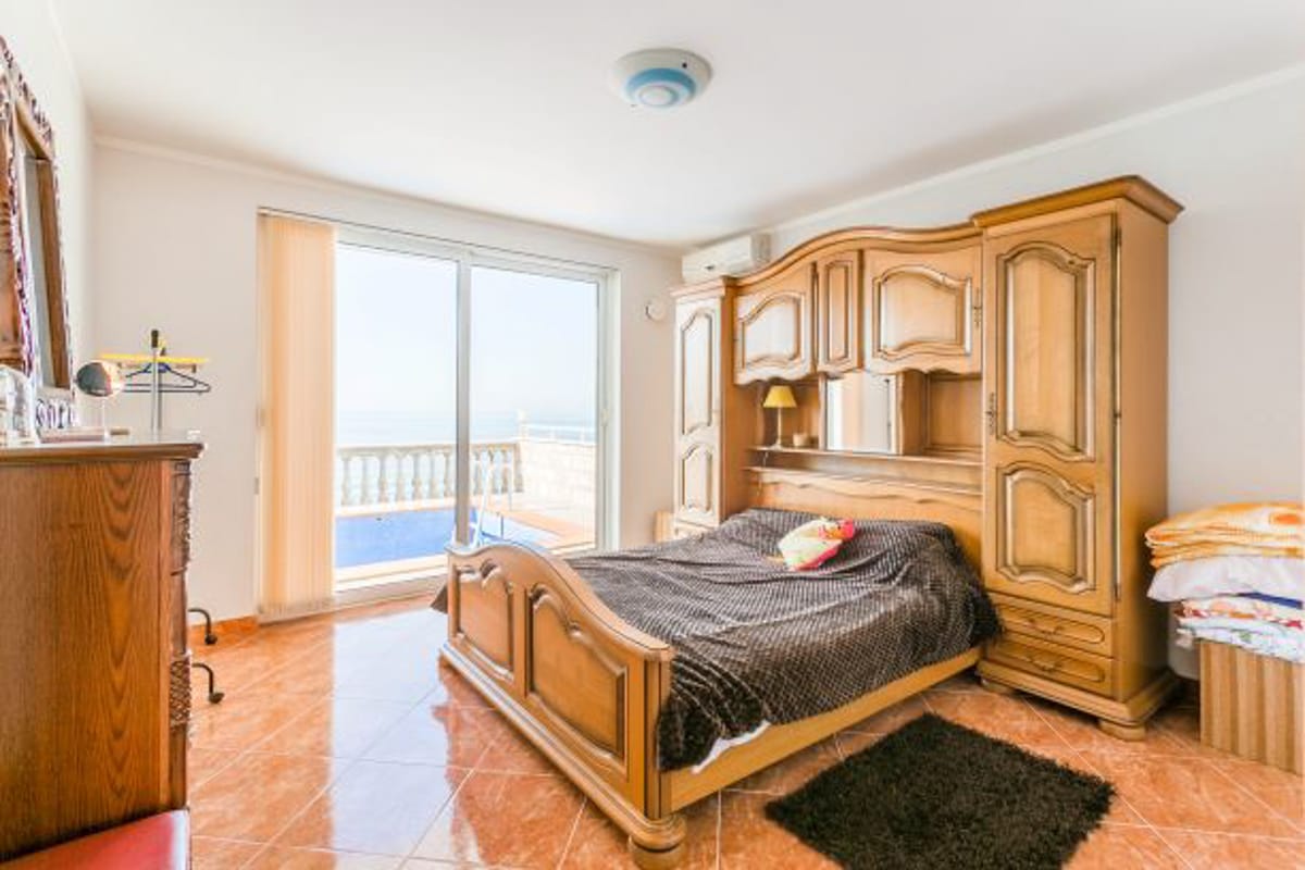 Bedroom in a house in Kruče, Montenegro: wooden furniture, tiled floor, and access to a terrace with sea and pool views.