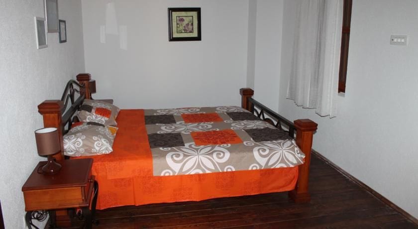 Bedroom with a double bed and wooden furniture in a villa in Krimovica, Montenegro. Cozy interior with bright textiles.