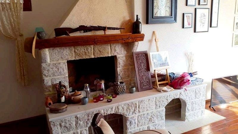Living room with a natural stone fireplace in a villa interior in Krimovice, Montenegro: decor, wooden shelf, and coziness.