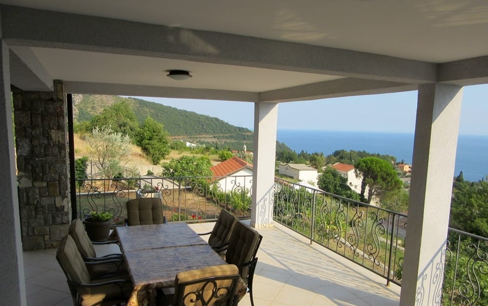 Spacious villa terrace in Reževići, Montenegro, with a dining area, wrought-iron railing, and panoramic sea views.