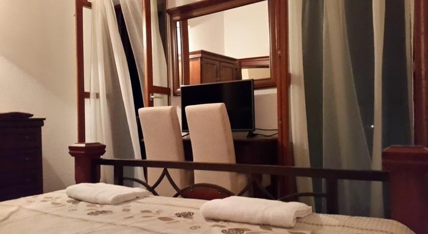 Cozy bedroom with a wooden bed, TV and mirror in a villa in Krimovica, Montenegro. Interior with soft furniture.