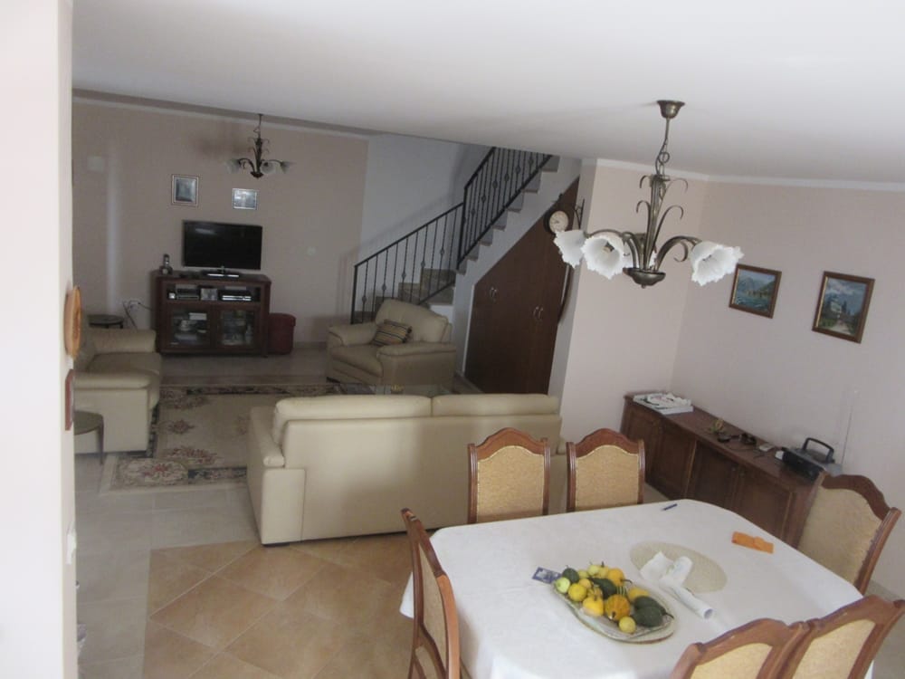 Spacious living room with dining area in a villa in Reževići, Montenegro: light furniture, staircase, and classic decor.