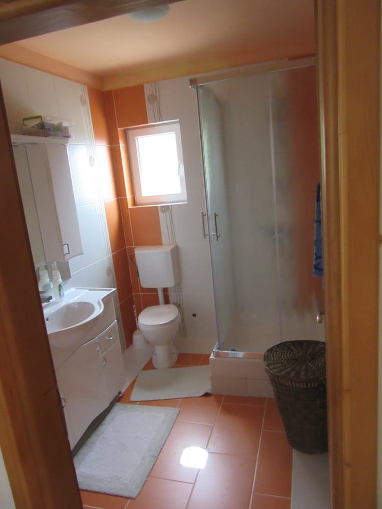 Bathroom with a shower cabin and orange tiles in a villa in Reževići, Montenegro: plumbing and furniture.