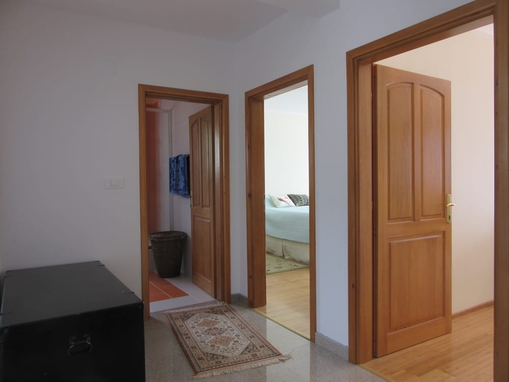 Hallway with wooden doors and a view of the bedroom in a villa, Reževići, Montenegro. Bright interior with a rug.
