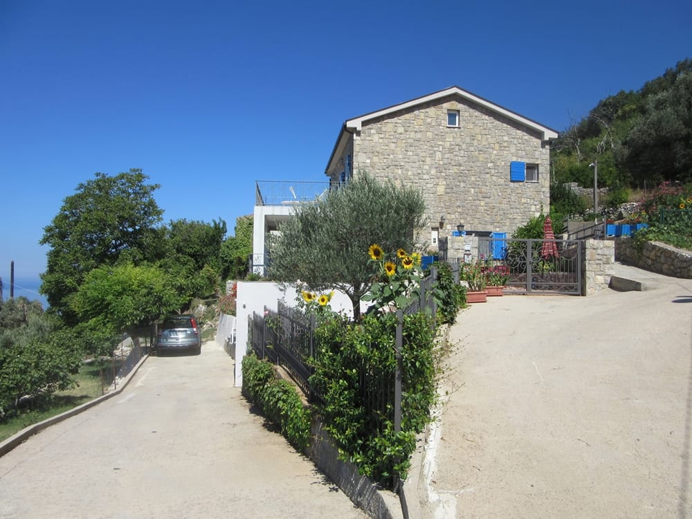 Two-story stone villa in Reževići, Montenegro: natural stone facade, terrace, garden, and parking by the house.