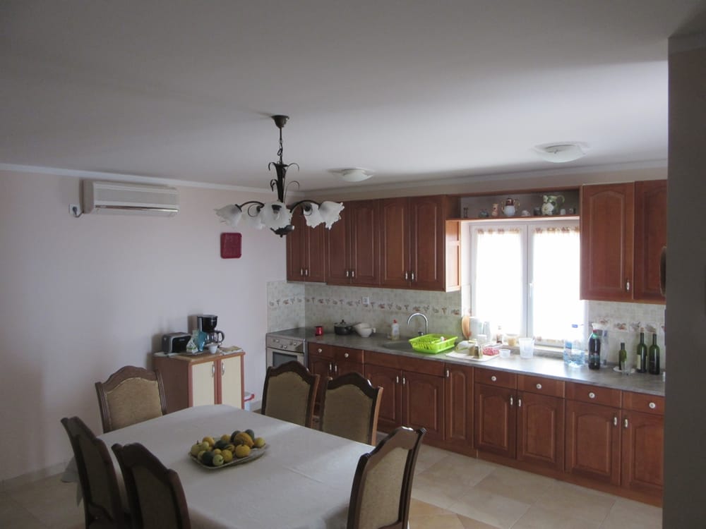 Kitchen with wooden cabinetry and dining area in a villa in Reževići, Montenegro: interior with air conditioning and furniture.