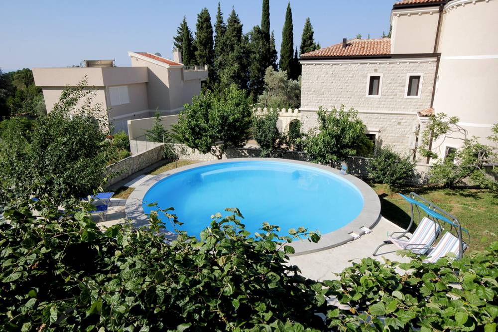 Round swimming pool in the courtyard of a private house in Reževići, Budva Riviera, Montenegro, with a relaxation area and garden.