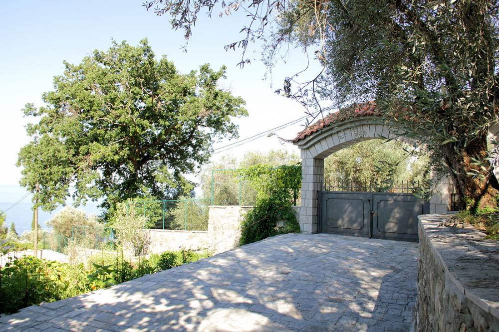 Entrance with a stone arch and gate by the house in Reževići, Budva Riviera, Montenegro, surrounded by olive trees.