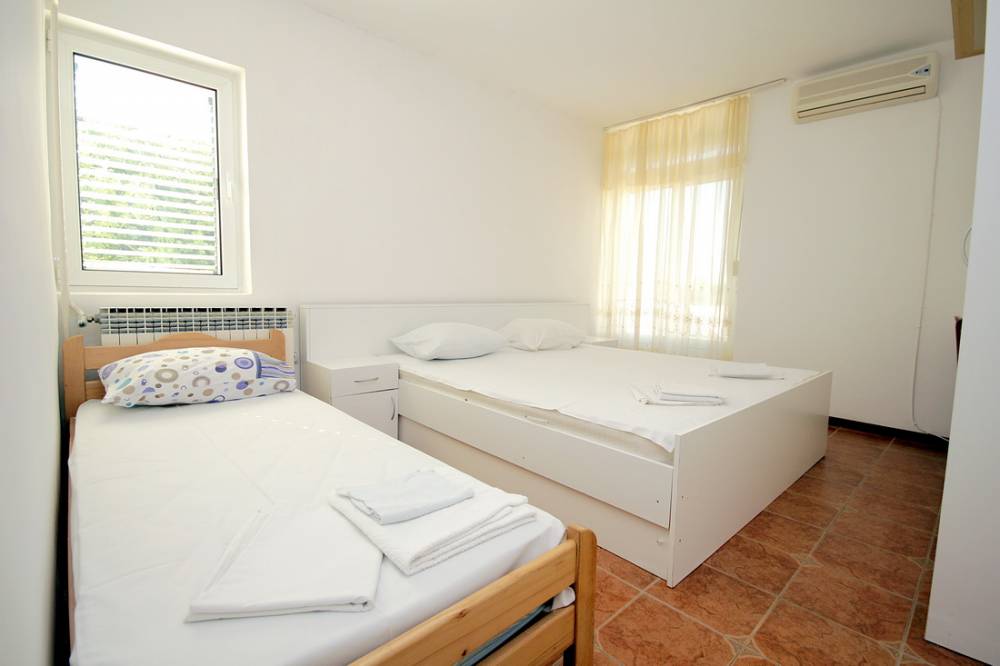 Bright bedroom with a double bed and a single bed in a house on the Budva Riviera, Montenegro, with air conditioning.