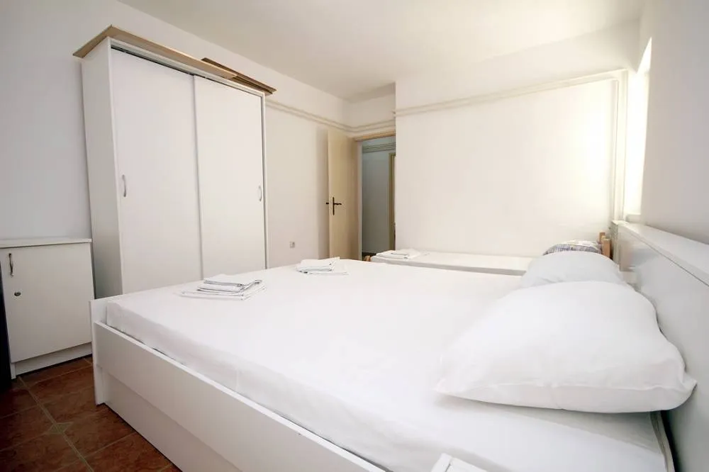 Bright bedroom featuring a white bed, sliding wardrobe, and folded towels on the floor.