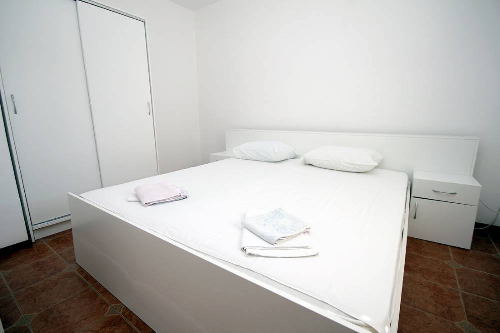 Bright bedroom with white furniture and a double bed in a house on the Budva Riviera, Montenegro.