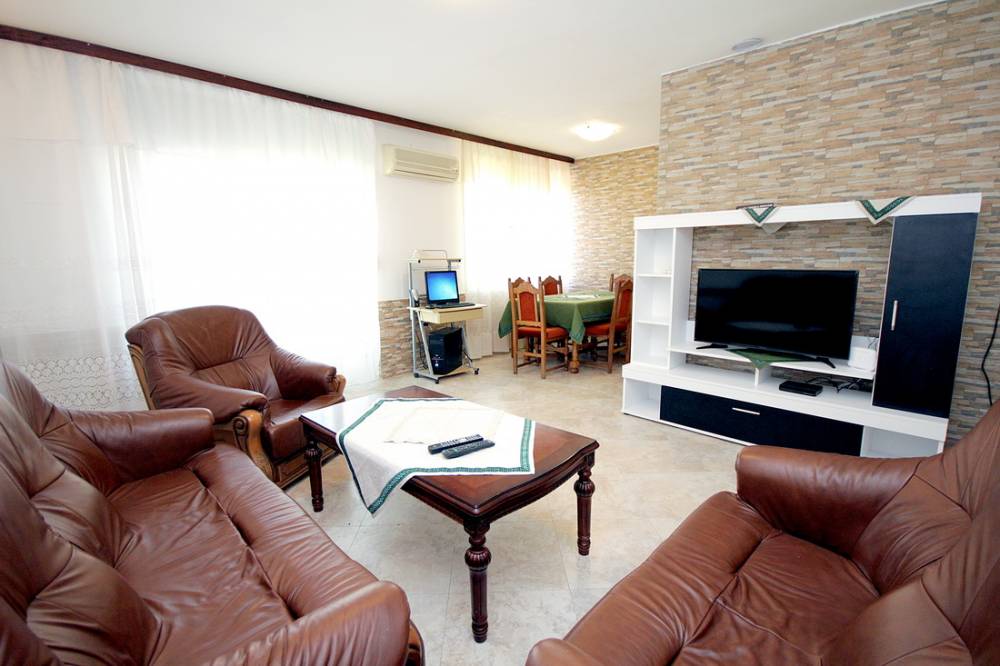 Living room in a house on the Budva Riviera, Montenegro: leather furniture, dining area, and stone finishes in the interior.