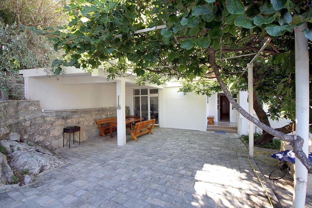 Cozy terrace with wooden furniture and a greenery canopy by the house in Reževići, Budva Riviera, Montenegro.