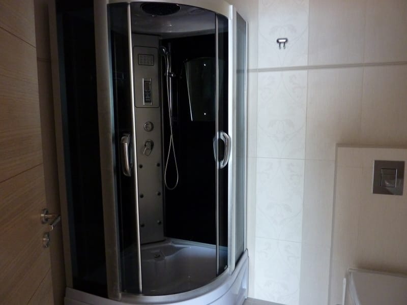 Modern shower cabin with hydromassage in the bathroom of an apartment in Pržno, Montenegro. Light tile finish.