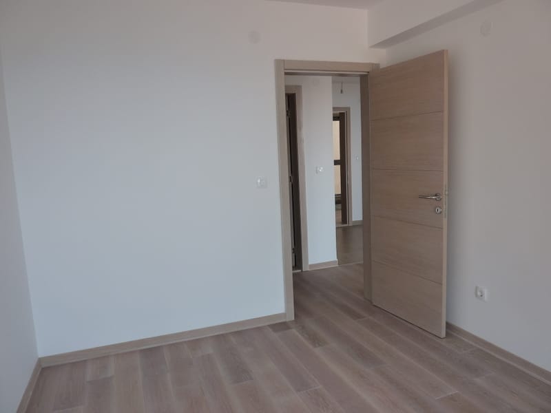 Bright living room with laminate flooring and an interior door in a new apartment in Pržno, Montenegro. Modern finishes.