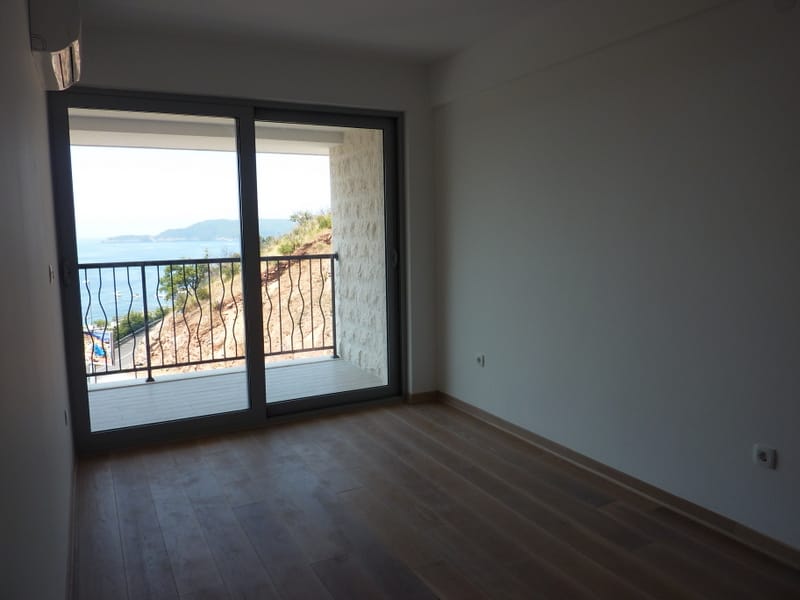 Bright living room in an apartment in Pržno, Montenegro, with panoramic sea views and access to a balcony with stone finishes.