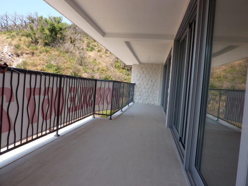 Spacious balcony with panoramic mountain views in an apartment in Pržno, Montenegro: modern finishes and railing.