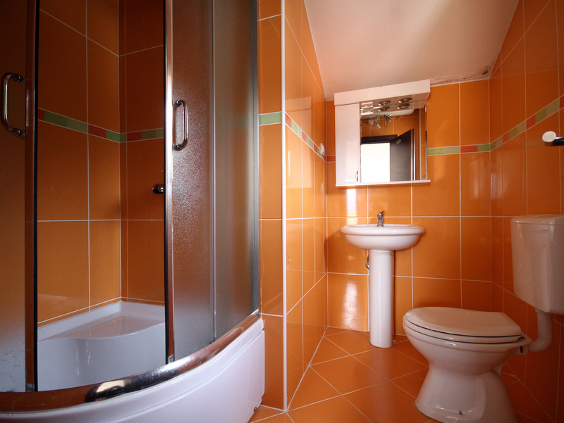 Bathroom in an apartment in Bečići, Montenegro: orange tiles, shower cabin, sink, and toilet.