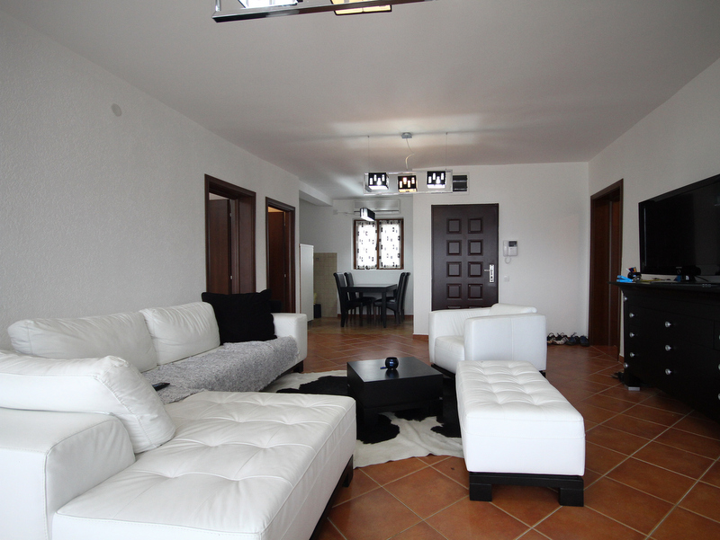 Bright living room with white leather furniture in an apartment for sale in Becici, Montenegro: modern interior with TV area.
