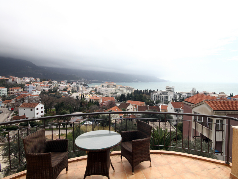 Balcony with wicker furniture and panoramic views of the sea and the city of Bečići, Montenegro. Apartment No. 1268 with a terrace.