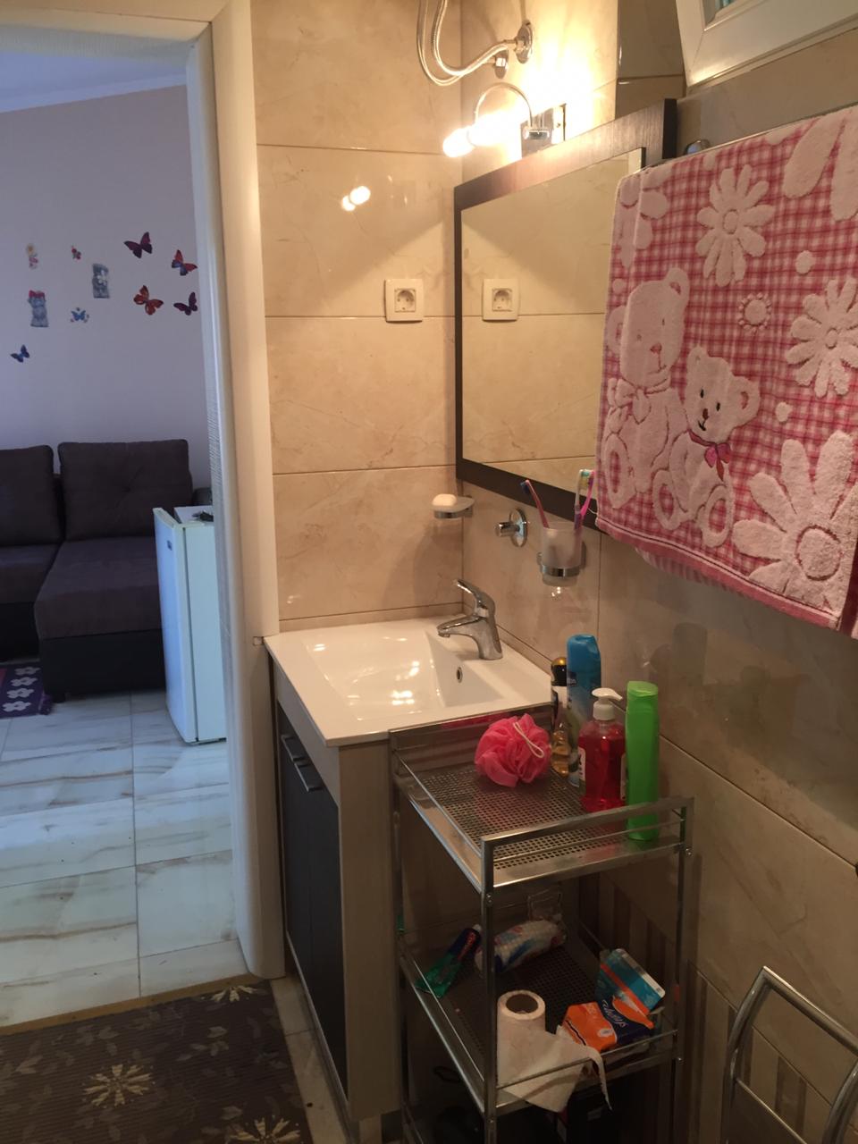 Bathroom with beige tiles and a mirror in a house in Shushan, Montenegro, view of the living area with a sofa.