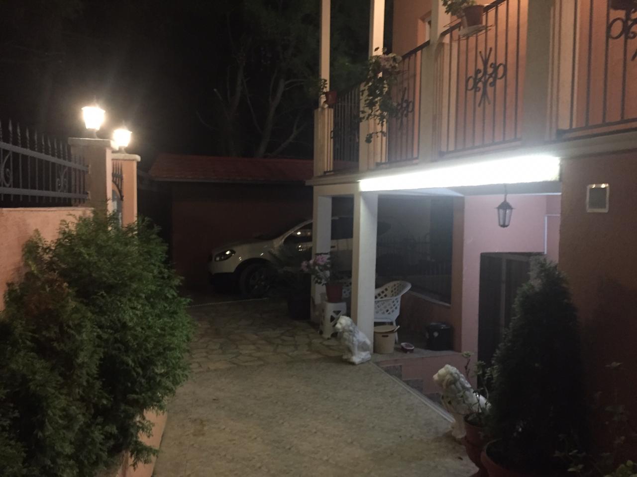 Two-story house in Shushan, Montenegro: night view of the private grounds, parking area, and lit terrace.