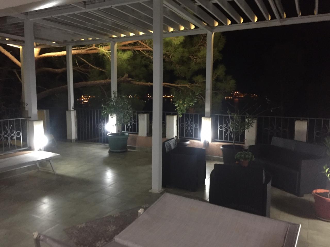 Evening terrace with furniture and sea view in a house in Šušanj, Montenegro: a cozy covered lounge area.