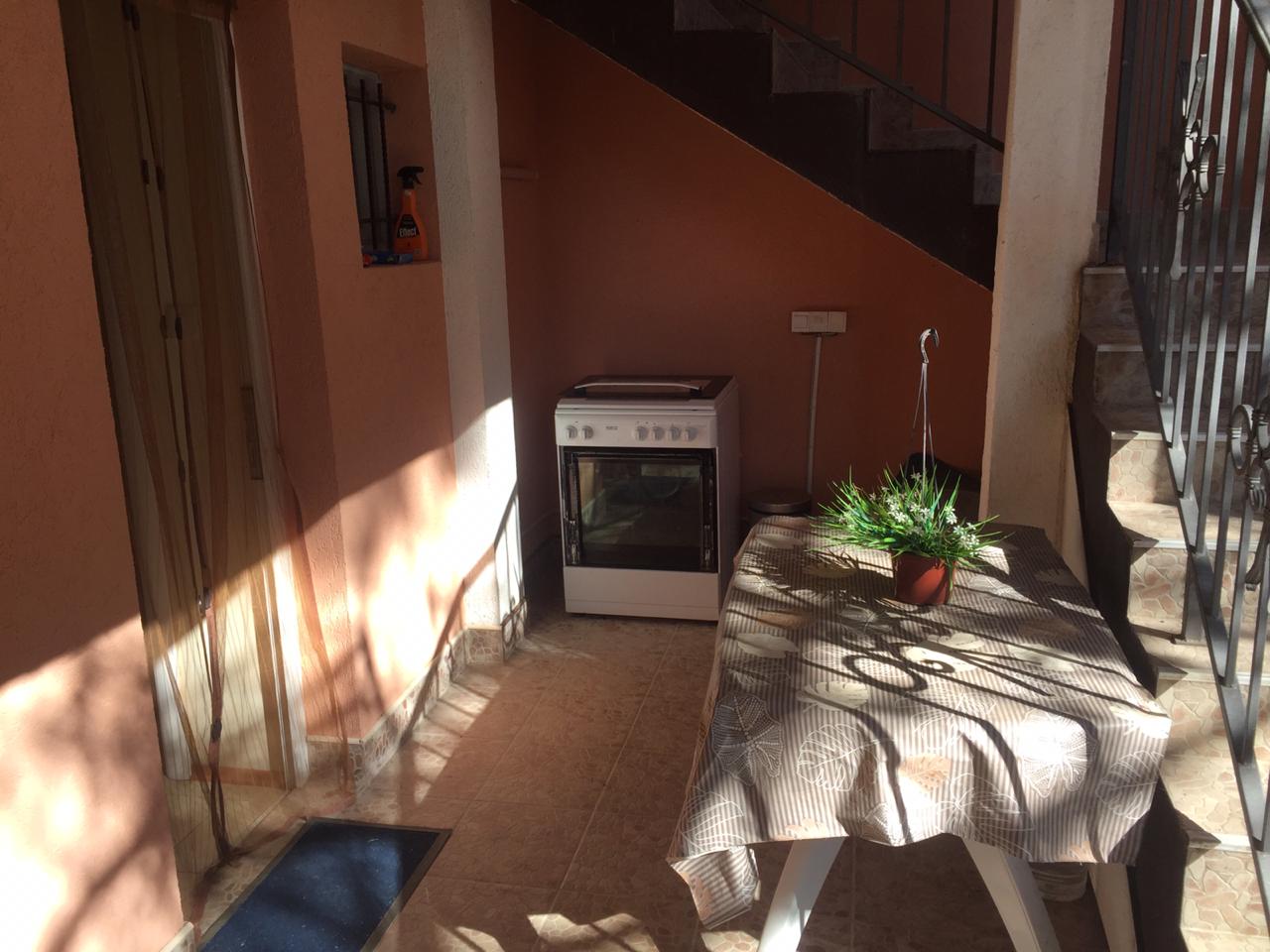 Summer kitchen on the terrace of a house in Shushan, Montenegro: stove, dining table, and staircase to the second floor.