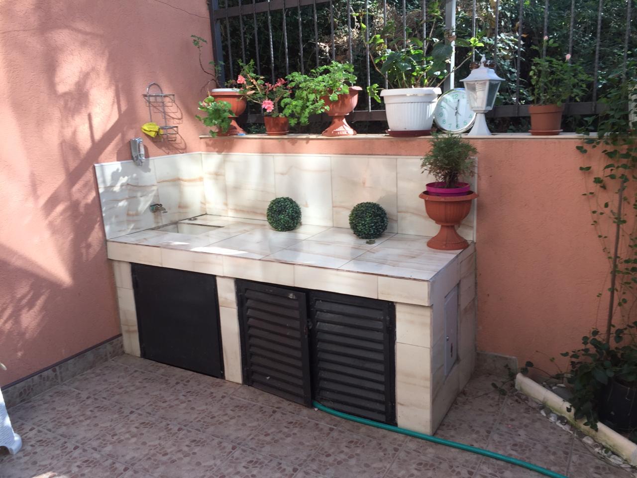 Summer kitchen on the terrace of a house in Shushan, Montenegro: tiled finish, sink, and garden decor with live plants.