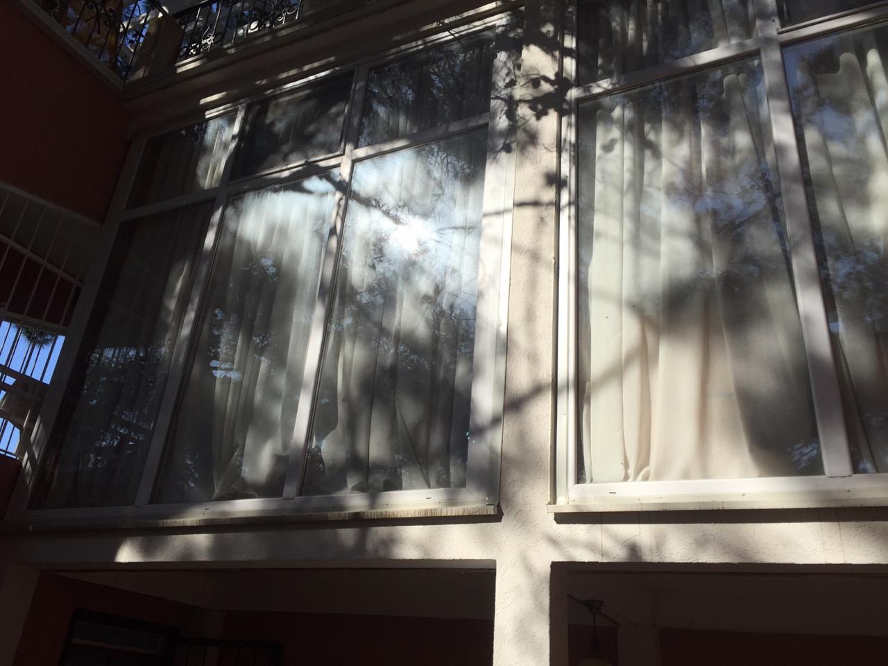 Panoramic windows of a house in Shushan, Montenegro: view of the facade with a terrace and trees reflected in the glazing.
