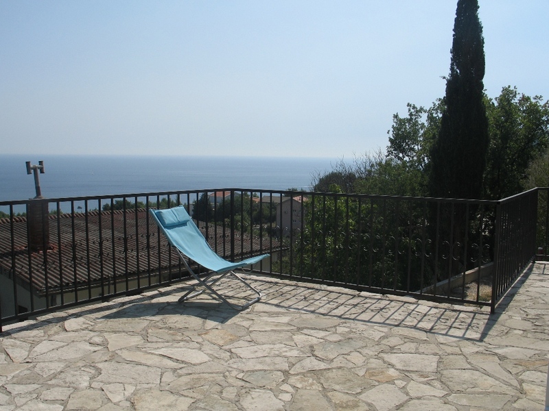 Terrace with sea view in a house, Sutomore, Montenegro: stone floor, wrought-iron railing, and a sun lounger for relaxing.