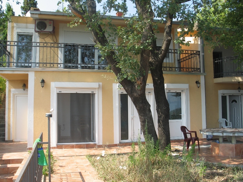 Two-story house with a terrace and garden in Sutomore, Montenegro: facade with panoramic doors and wrought-iron balconies.