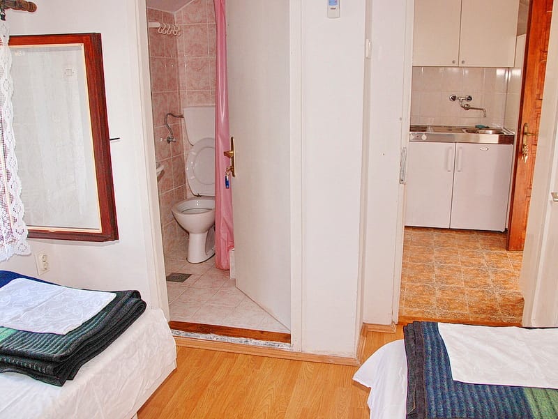 Bedroom interior with an en-suite bathroom and kitchenette in a house, Igalo, Montenegro. Compact apartment with furniture and finishes.