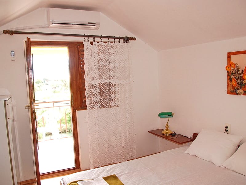 Bedroom in a house in Igalo, Montenegro: double bed, balcony access, air conditioning, and wall decor.
