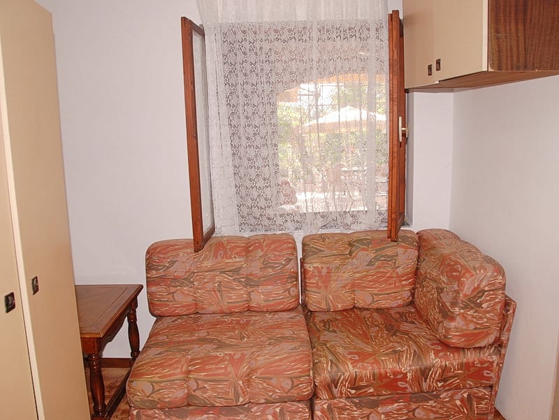 Living room with a comfortable sofa and garden view in a house in Igalo, Montenegro: cozy interior with wooden furniture.