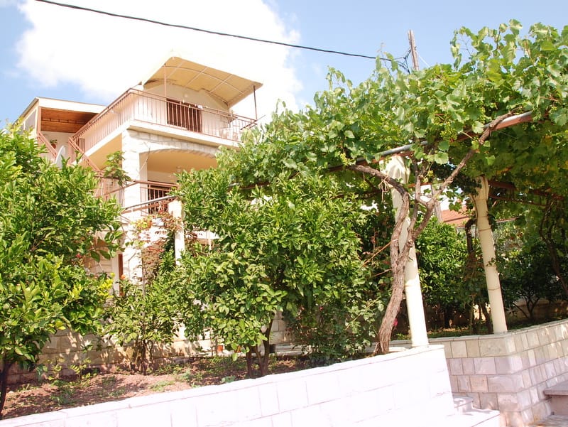 Two-story house with terraces and a garden with a vineyard in Igalo, Montenegro: view of the facade and the surrounding grounds.