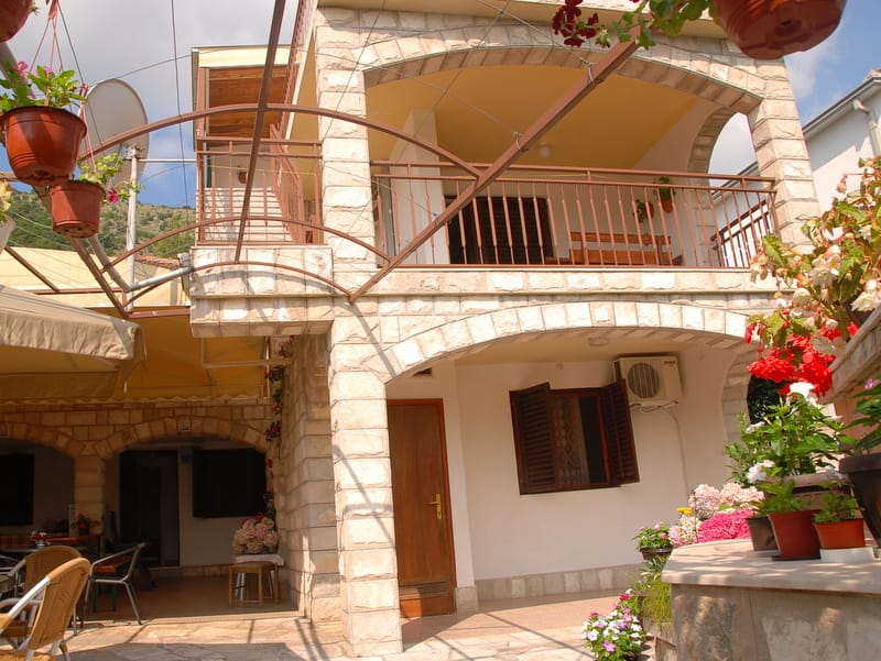 Two-story stone house with a terrace and garden in Igalo, Montenegro: exterior view of the facade with arched elements.